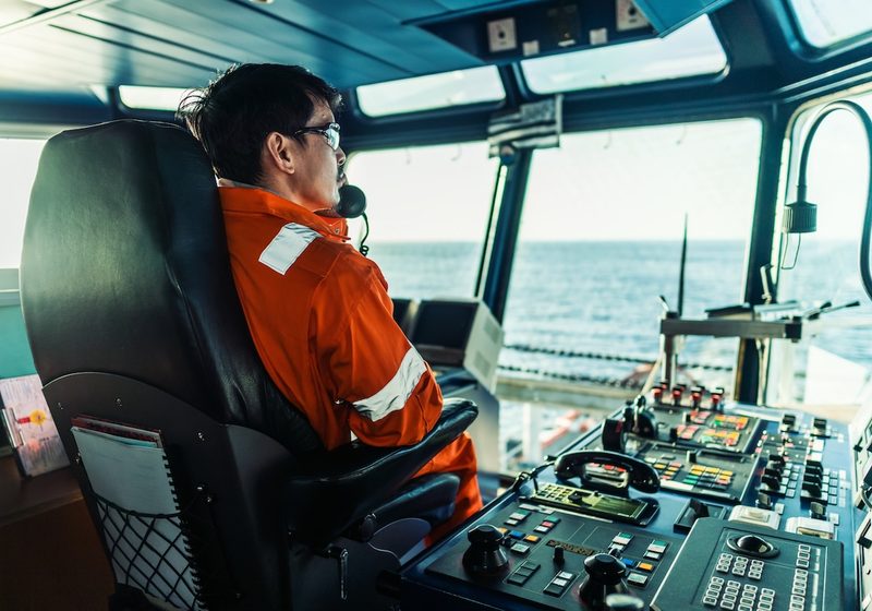 Comandante seduto in plancia davanti alle strumentazioni: chi siamo, Universo GMDSS Italia